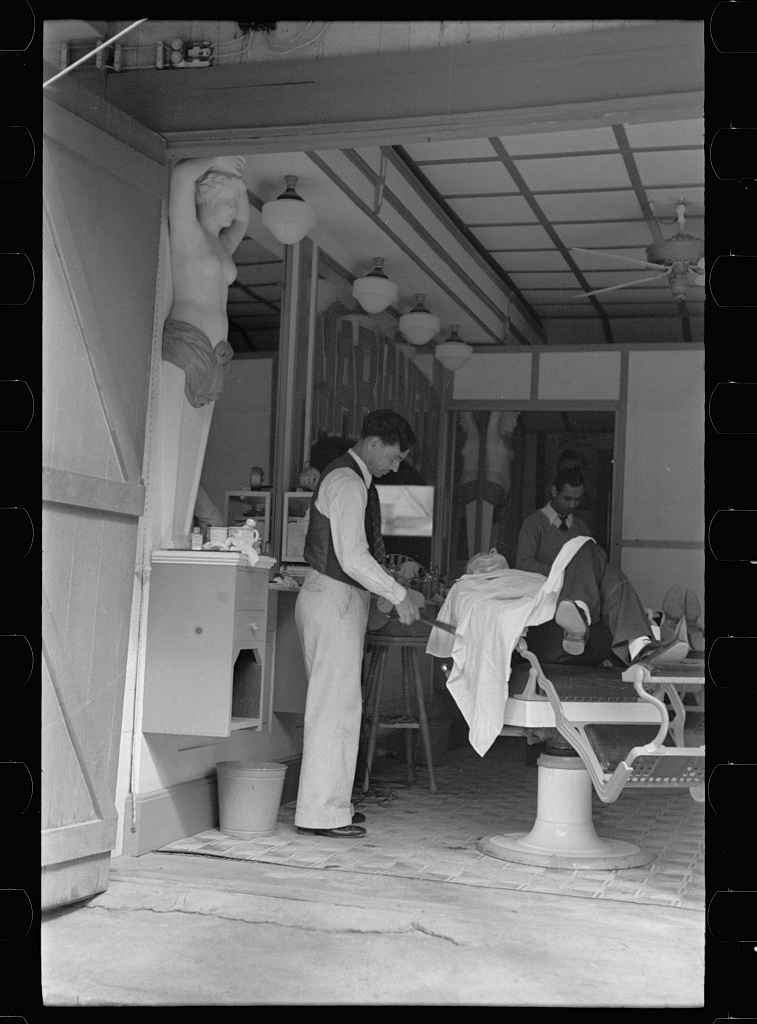 A barbershop in Key West, 1938. The razor and the red pencil. Both require a steady hand.